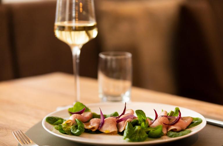 Insalata con carne e cipolle, accompagnata da un bicchiere di vino bianco.