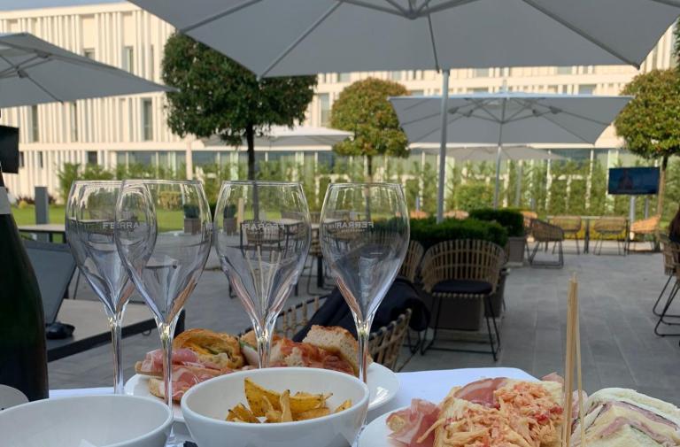 Aperitivo all'aperto con snack e calici di vino in un ambiente elegante.